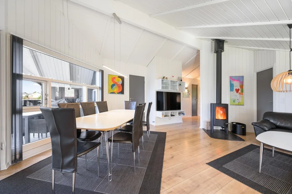 A bright dining and living area with a long table and a freestanding stove.