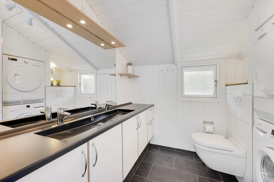 A bright bathroom with a long countertop, sink, and toilet.