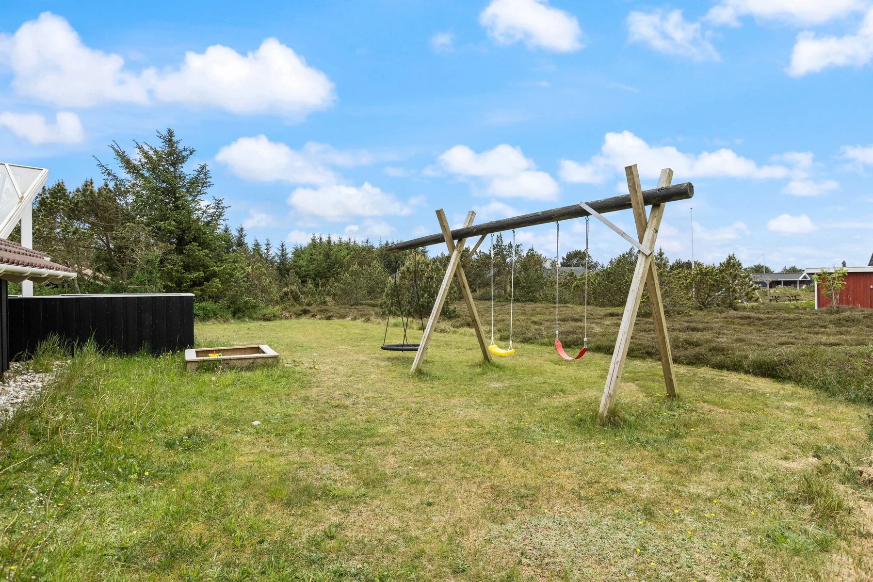 An outdoor play area with a wooden swing set on a grassy lawn.