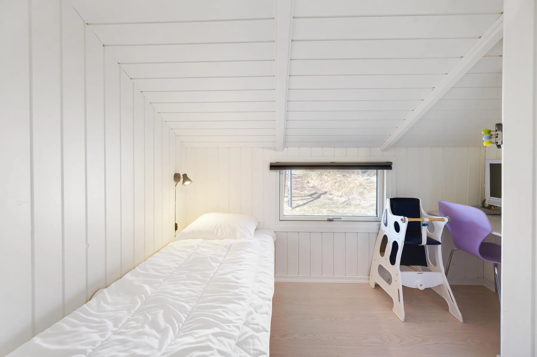A bright bedroom with a single bed and a small table by the window.