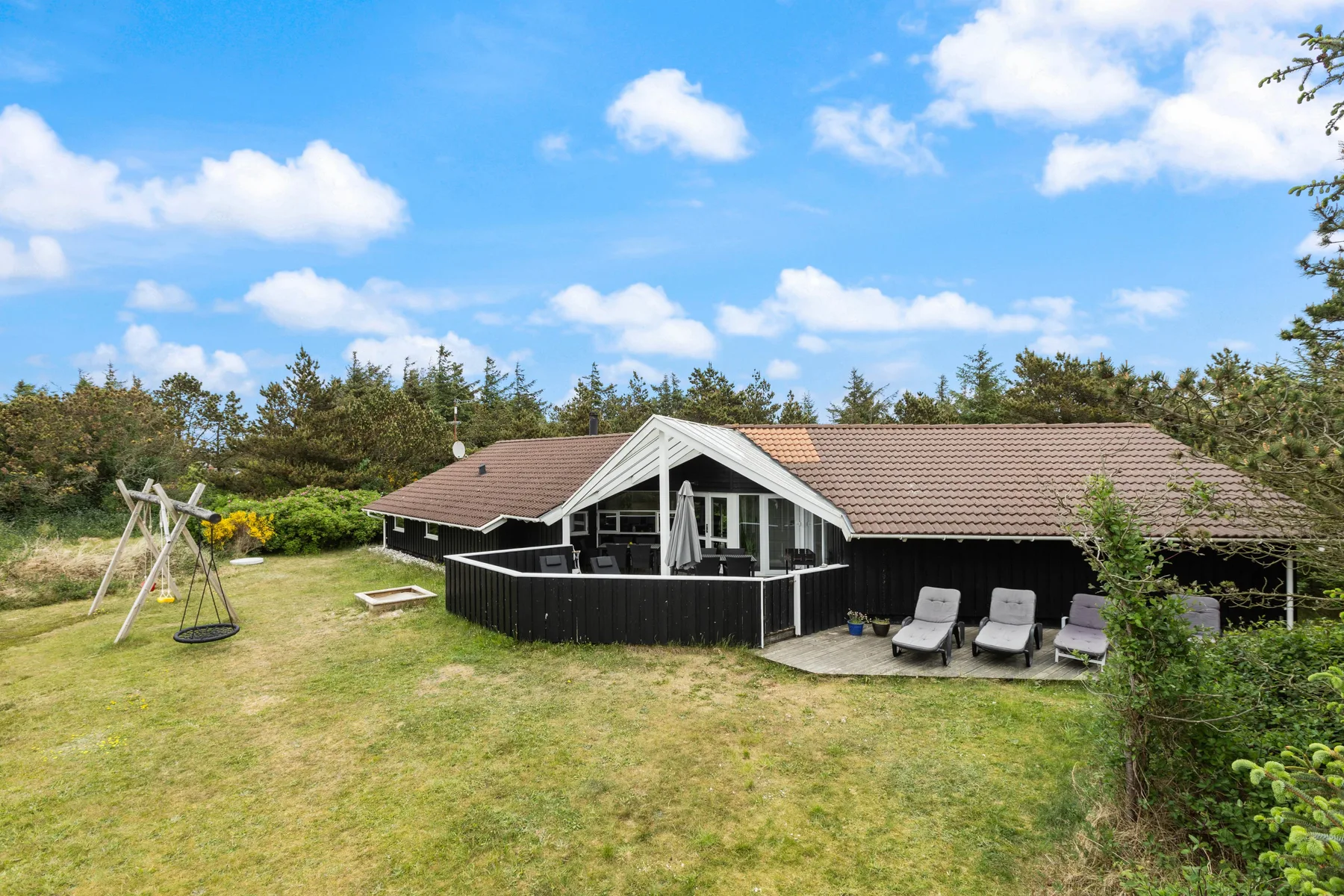 A single-story holiday house opens onto a grassy yard with outdoor seating.