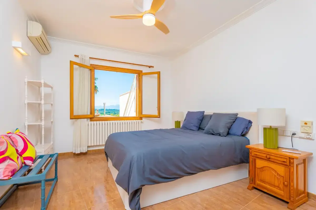 Un dormitorio con una cama grande y una ventana abierta con vistas al mar.