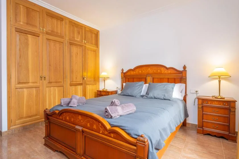 Un dormitorio con una cama de madera, un armario a juego y mesitas de noche.