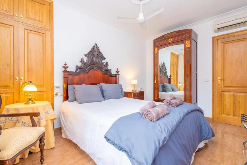 Un dormitorio con una cama grande, armarios de madera y un ventilador de techo.
