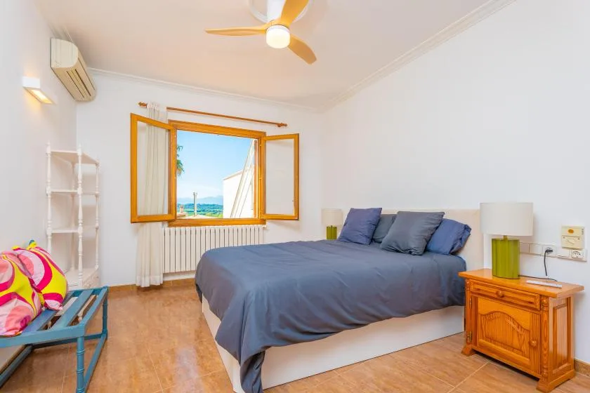 Un dormitorio con una cama junto a una ventana abierta con vistas al agua.