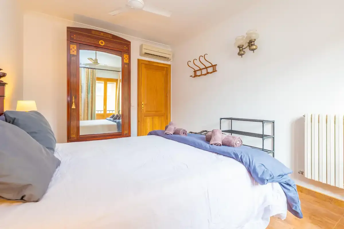 Un dormitorio con una cama grande, un espejo de pared y una puerta de madera.