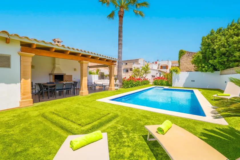 Un patio soleado da a una piscina azul y un césped verde.