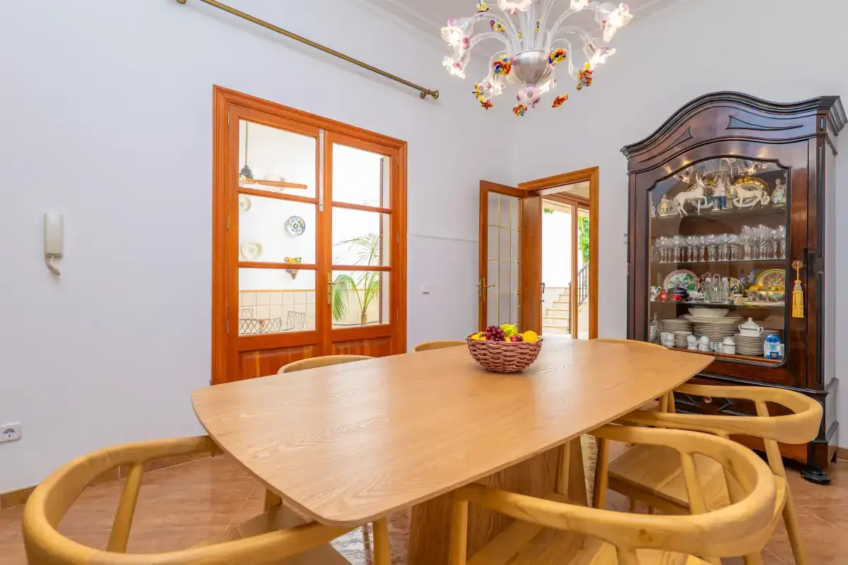 Un comedor con una mesa de madera y un aparador con puertas de cristal.