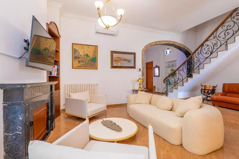 Una sala de estar con asientos claros, una chimenea y una escalera.