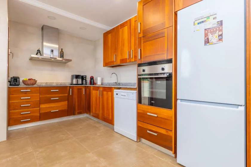 Una cocina con armarios de madera, una encimera y electrodomésticos integrados.