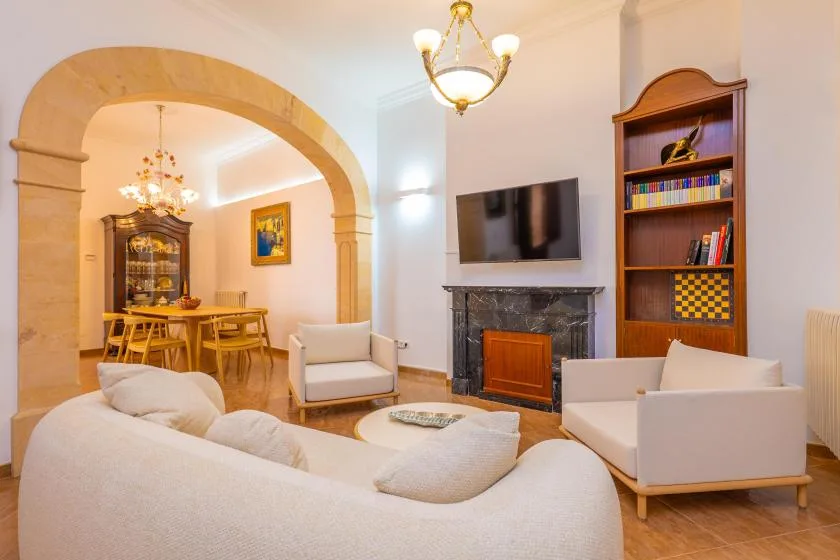 Una sala de estar con asientos, una chimenea y un arco que da a un comedor.
