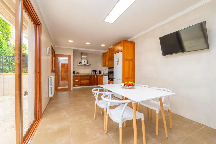 Una luminosa cocina y zona de comedor con armarios de madera y una mesa blanca.
