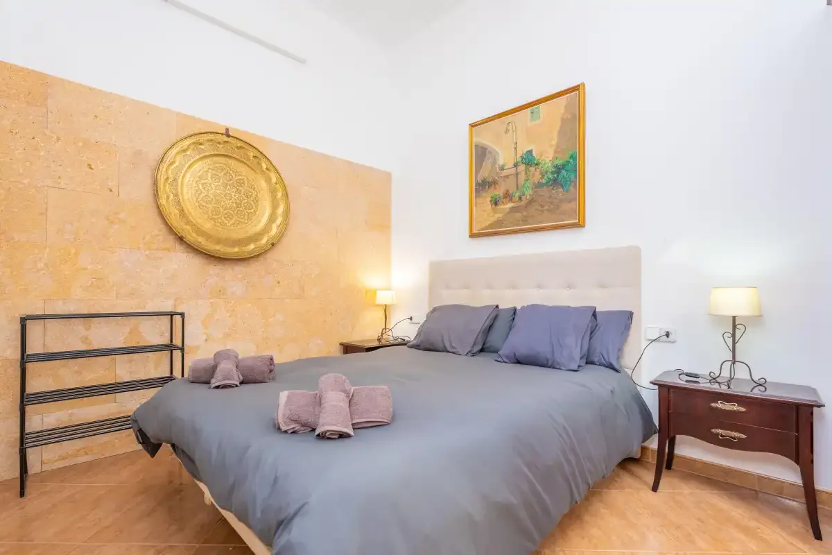 Un dormitorio con una cama grande, mesillas de noche y cuadros en la pared.