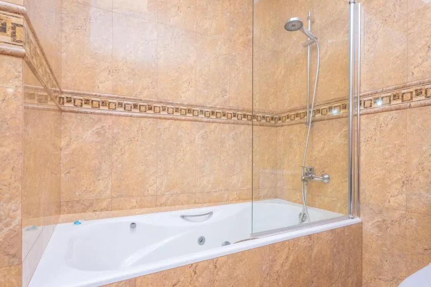 Un baño alicatado con bañera y ducha de pared.