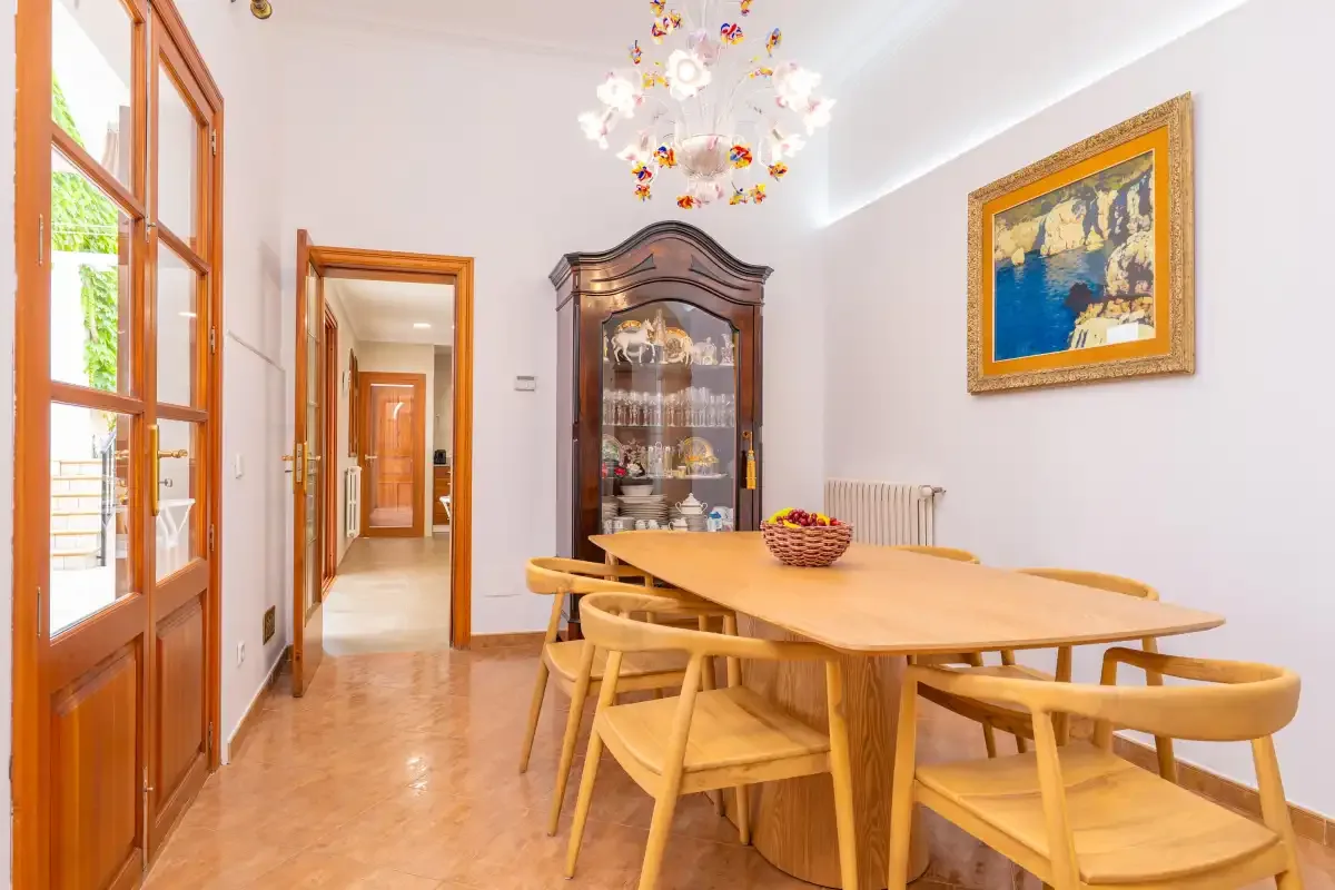 Comedor con una mesa de madera y sillas junto a ventanas altas.
