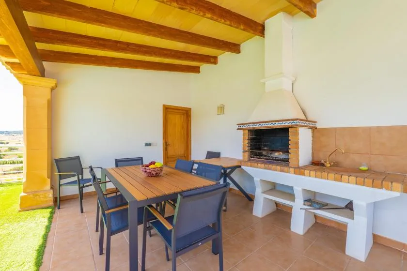 Un patio cubierto con una mesa de comedor y una barbacoa empotrada.