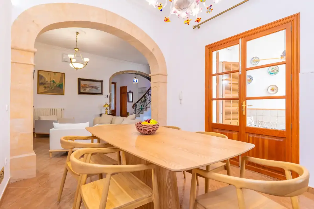 Un comedor con una mesa de madera y asientos junto a un arco.