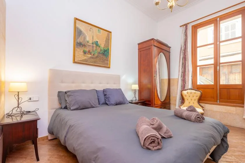 Un dormitorio con una cama grande, mesitas de noche y un armario de madera.