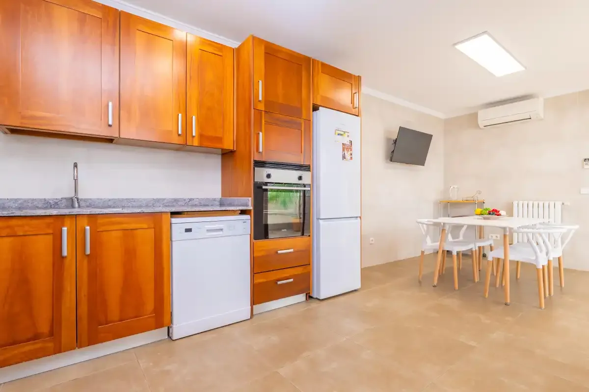Una cocina se abre a un comedor con una mesa y sillas.