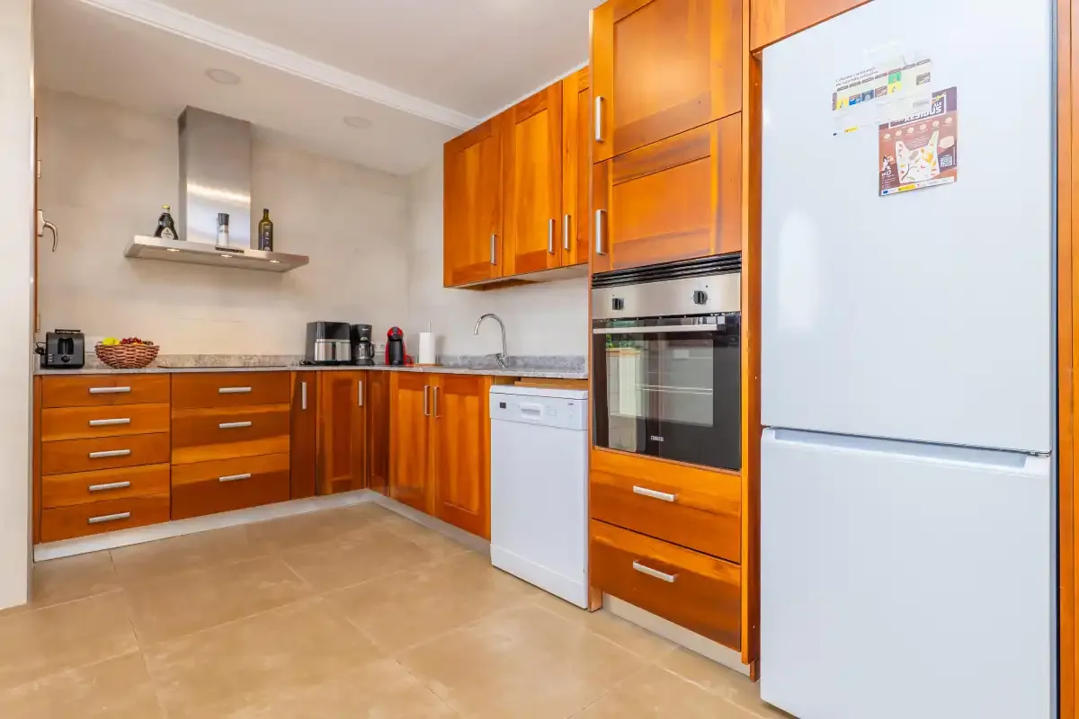 Una cocina con armarios de madera, un refrigerador y un horno.