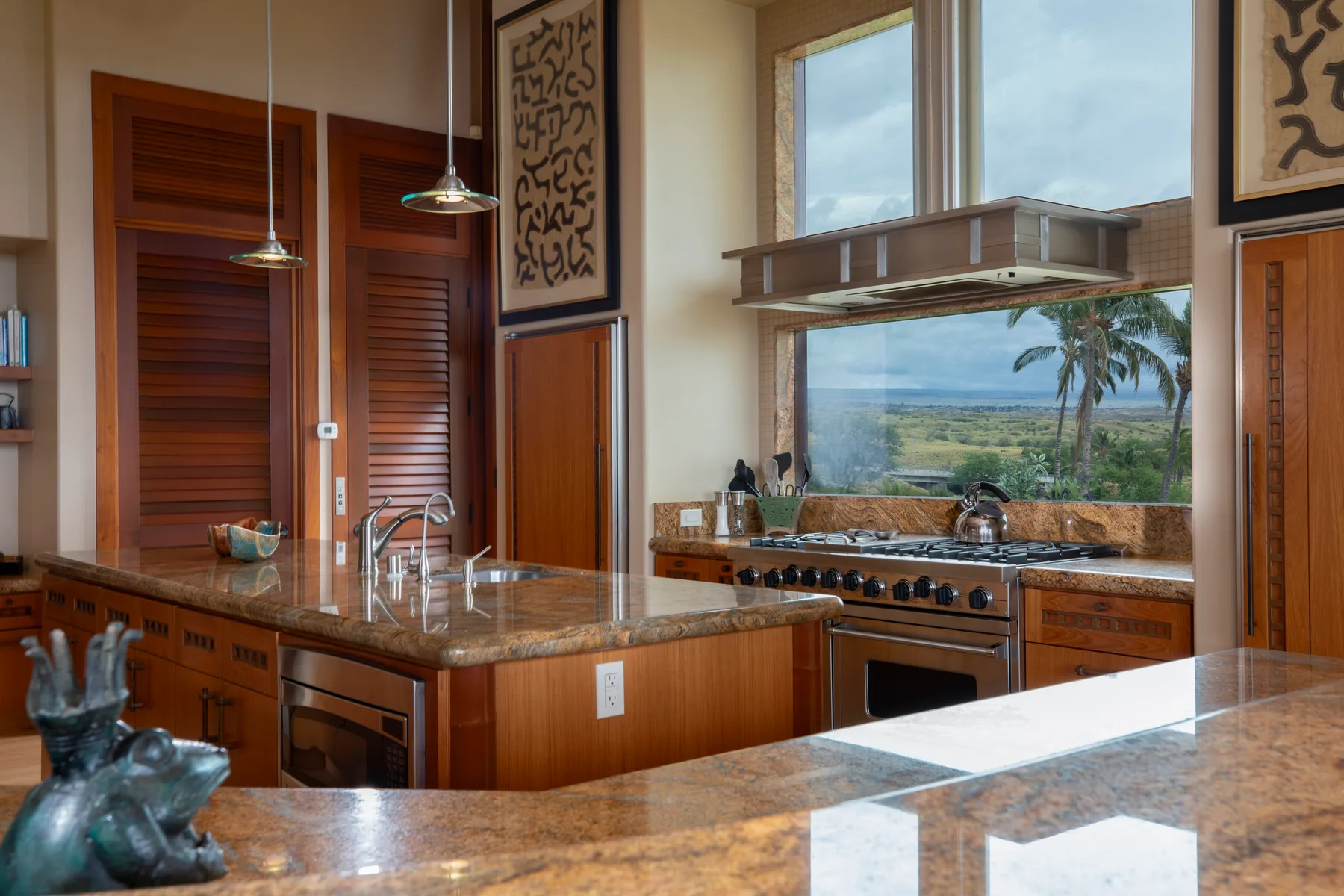 Una cocina con gabinetes de madera, una isla central y una amplia ventana con vistas al paisaje.