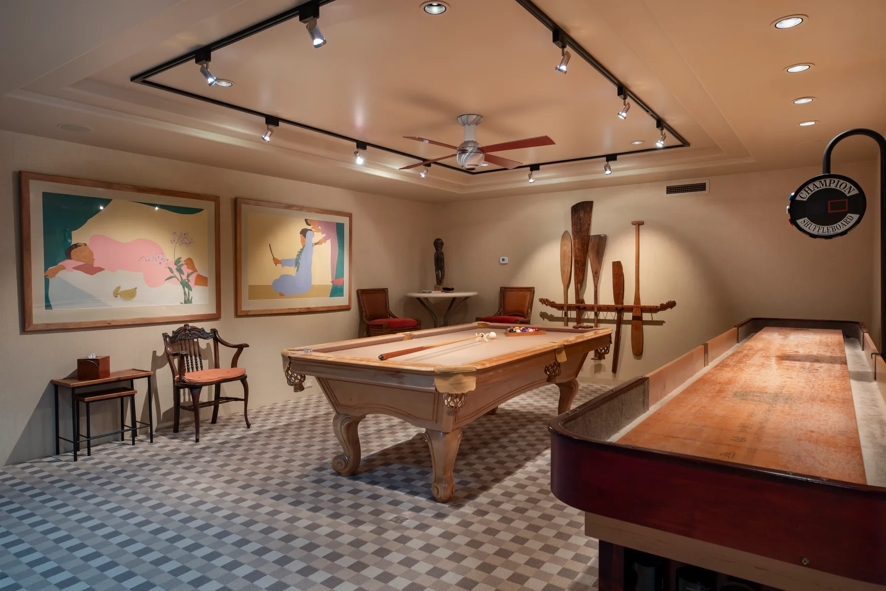 Una sala de billar con una mesa de pool, cuadros y luces en rieles.