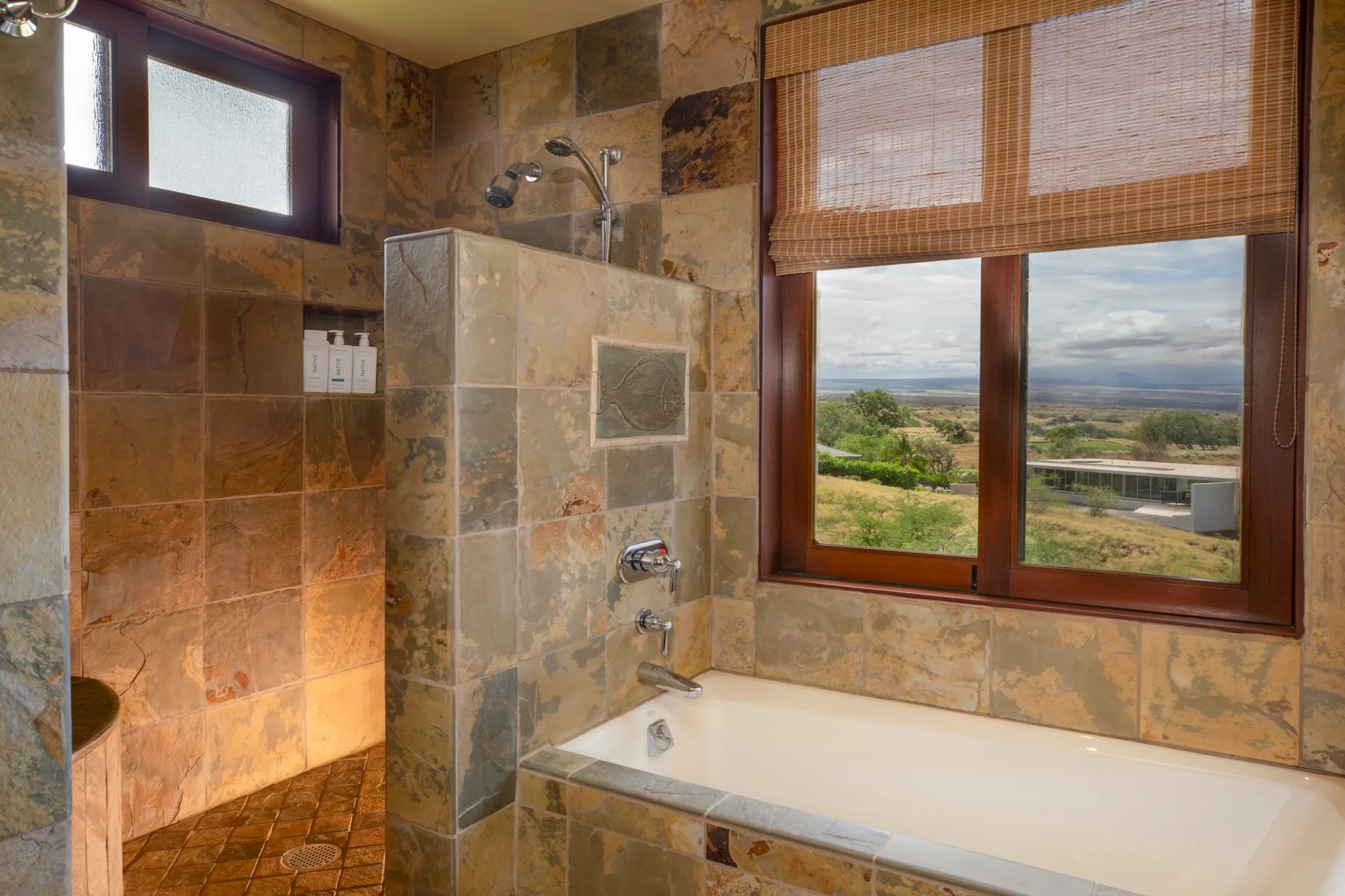 Un baño alicatado con bañera y una ventana grande con vistas al paisaje.