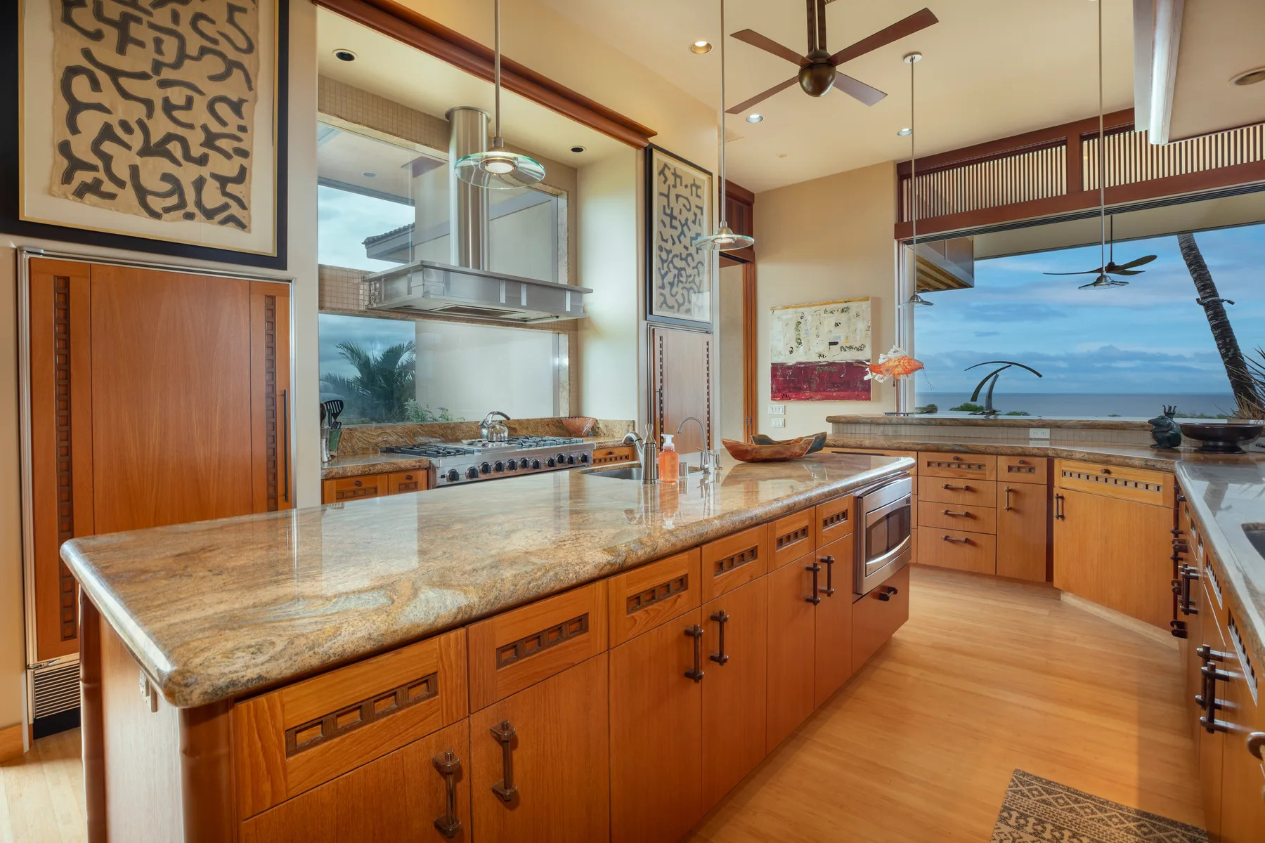 Una cocina amplia con gabinetes de madera, una isla grande y vistas al mar.