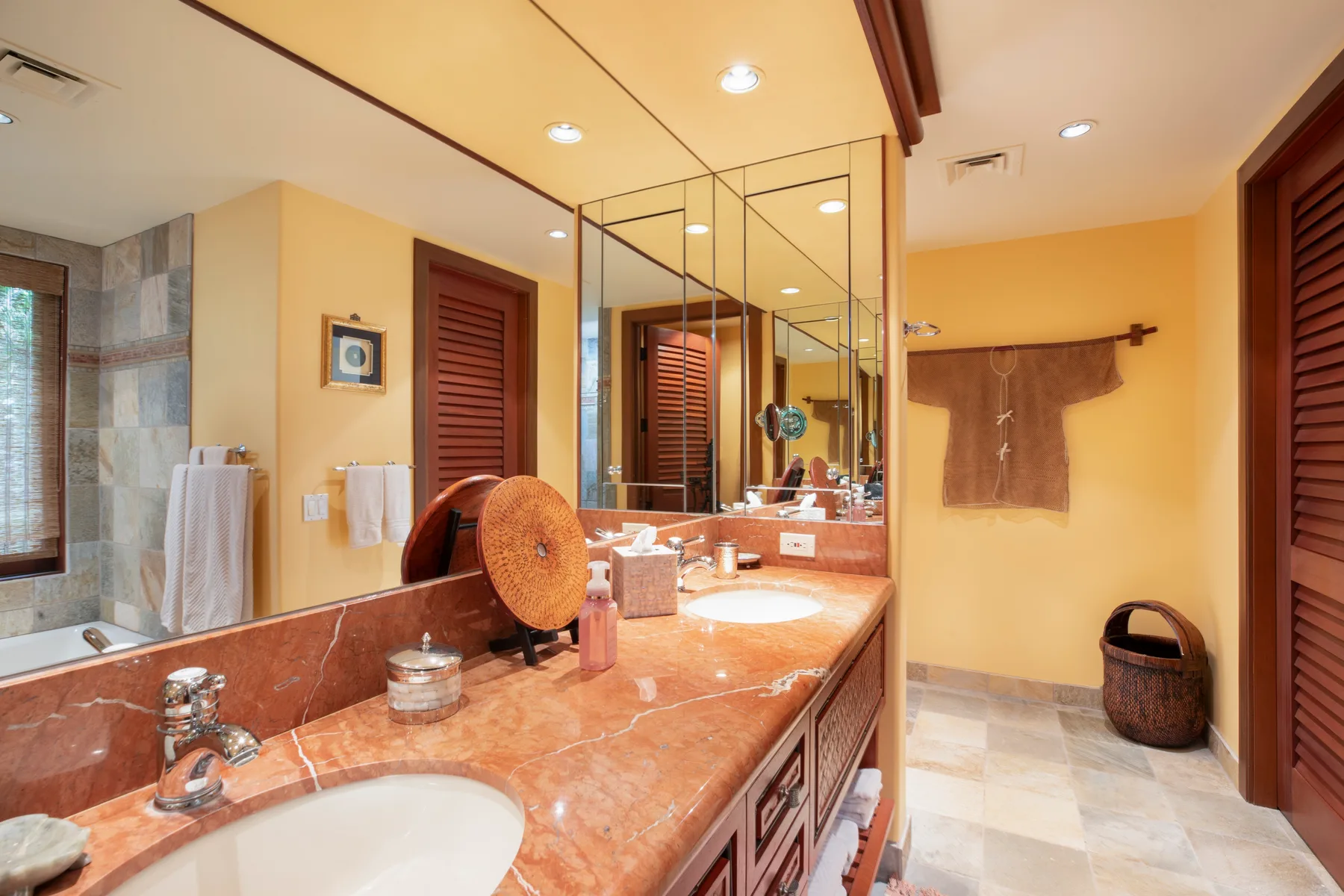 Un baño con un tocador largo, lavabos y una gran pared de espejos.