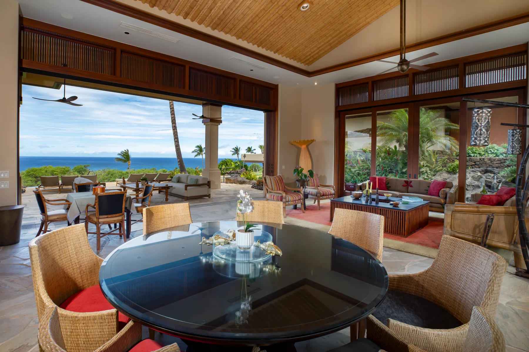 Sala y comedor diáfanos con una mesa de vidrio y vistas al océano.