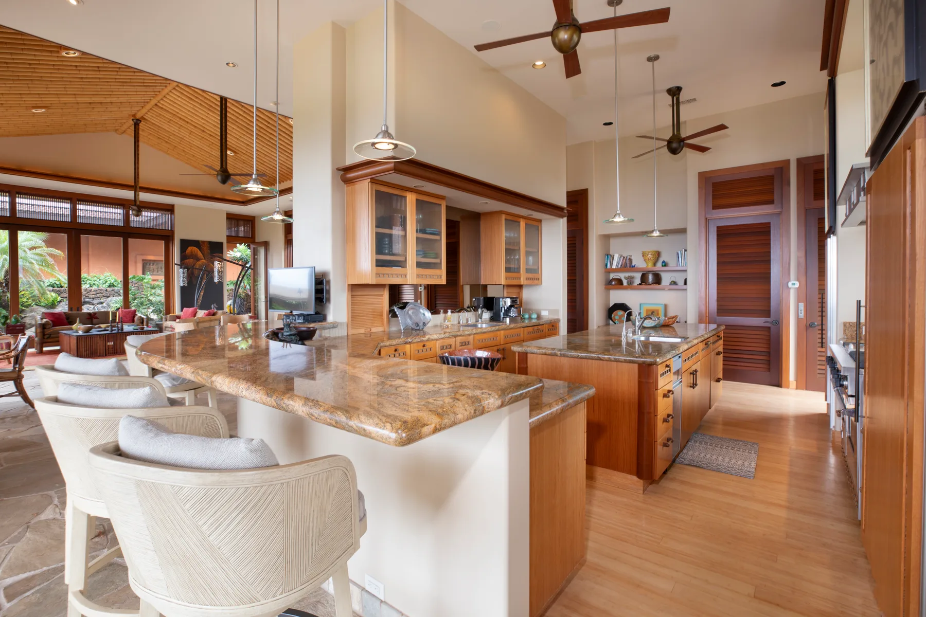 Una cocina luminosa con una isla grande y gabinetes de madera se abre a un comedor.