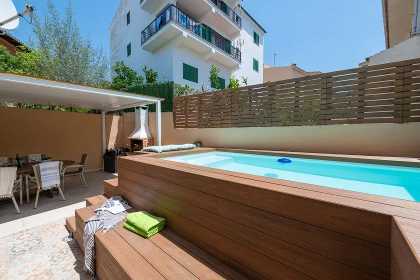 Una pequeña piscina exterior está junto a un patio sombreado con asientos.