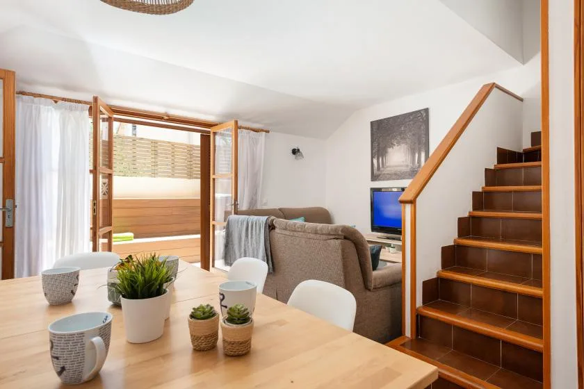 El comedor se abre a una sala de estar junto a una escalera de madera.