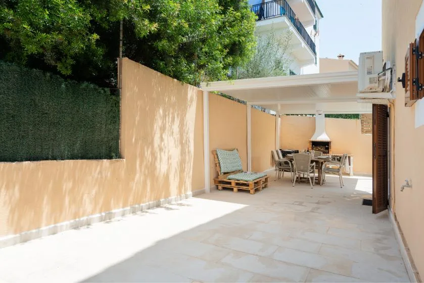 Un patio pavimentado con asientos al aire libre bajo un toldo blanco.