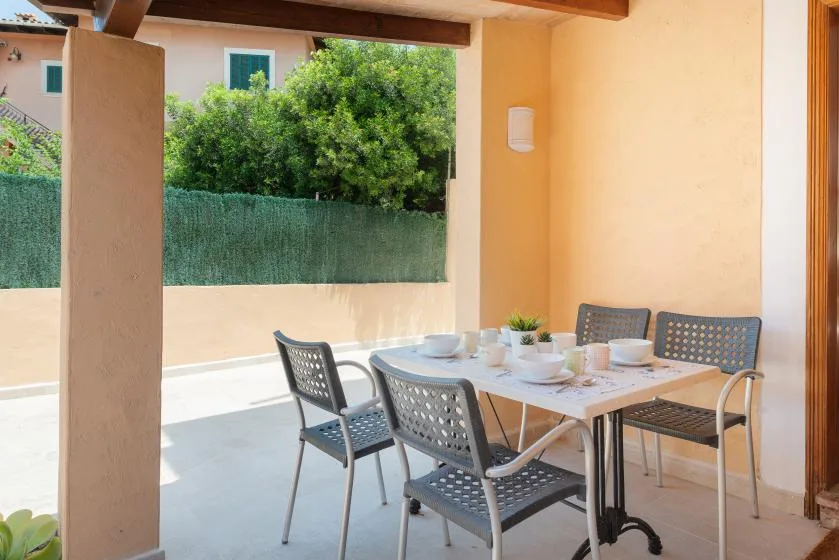 Un patio cubierto con una mesa de comedor y asientos junto a un seto verde.