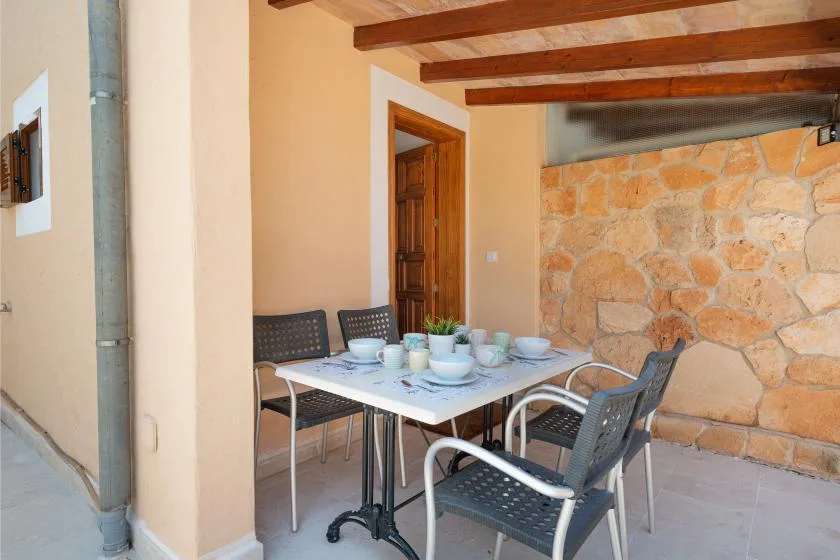Un comedor con una mesa y sillas junto a una pared de piedra.