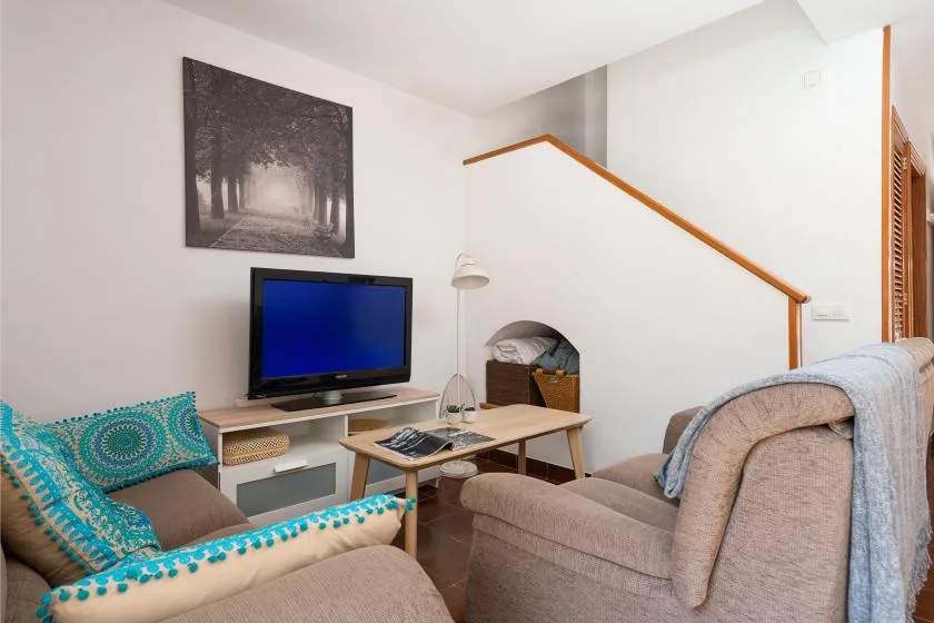 Una sala de estar con asientos, un televisor y una escalera.