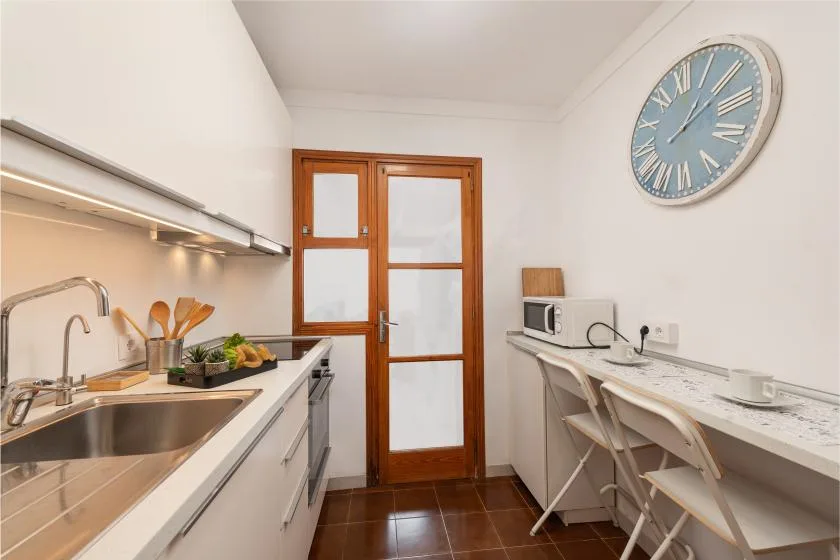 Una cocina compacta con una encimera, fregadero y taburetes junto a la pared.