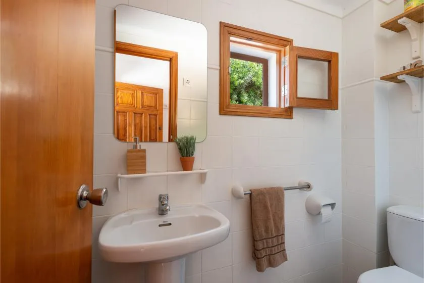 Un baño con lavabo, espejo y una ventana pequeña.