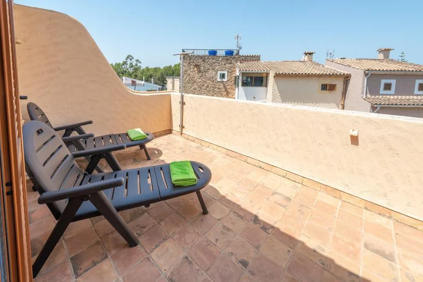Una terraza con suelo de baldosas y asientos al aire libre da a los tejados cercanos.