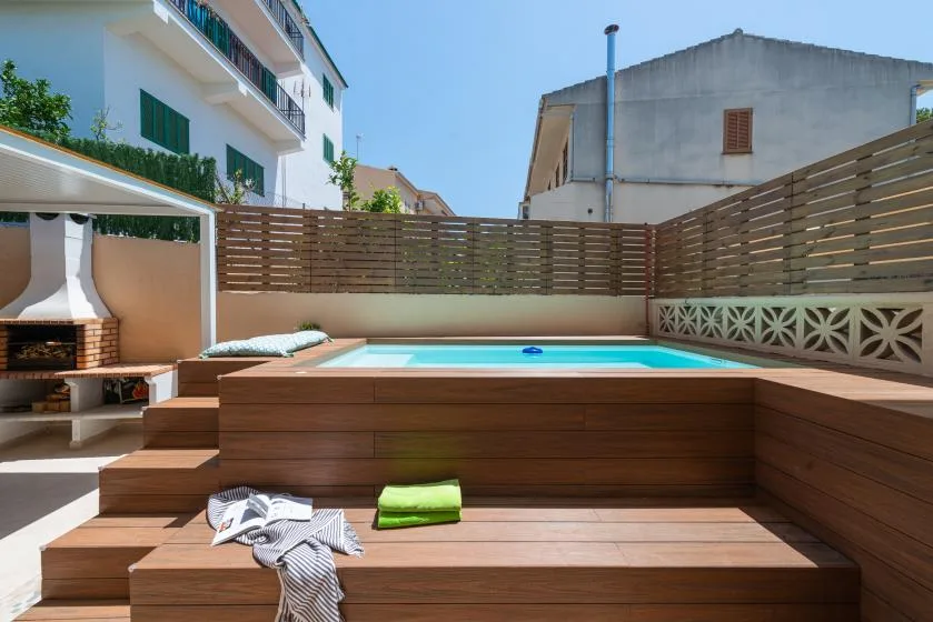 Una pequeña piscina exterior está junto a una tarima de madera y una zona para sentarse.