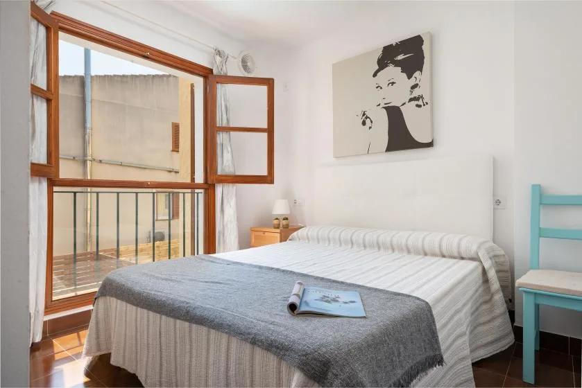 Un dormitorio con una cama bien tendida y grandes ventanas con vistas a un balcón.