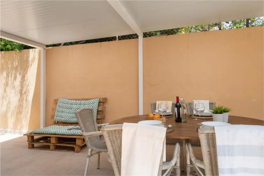 Comedor exterior cubierto con una mesa redonda y asientos tejidos.