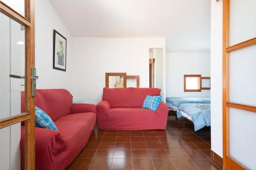 Una habitación luminosa con asientos rojos y una cama cubierta con ropa de cama azul.