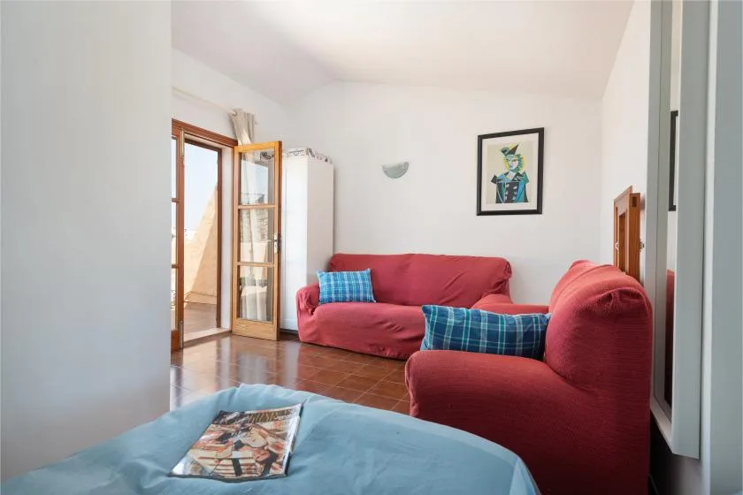 Una sala luminosa con asientos rojos y una puerta abierta al balcón.