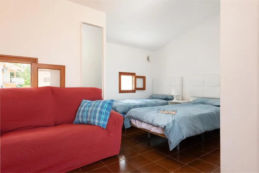 Un dormitorio con dos camas y un sofá rojo en primer plano.