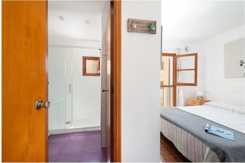 Un dormitorio con un baño contiguo y una cama cubierta con ropa de cama gris.