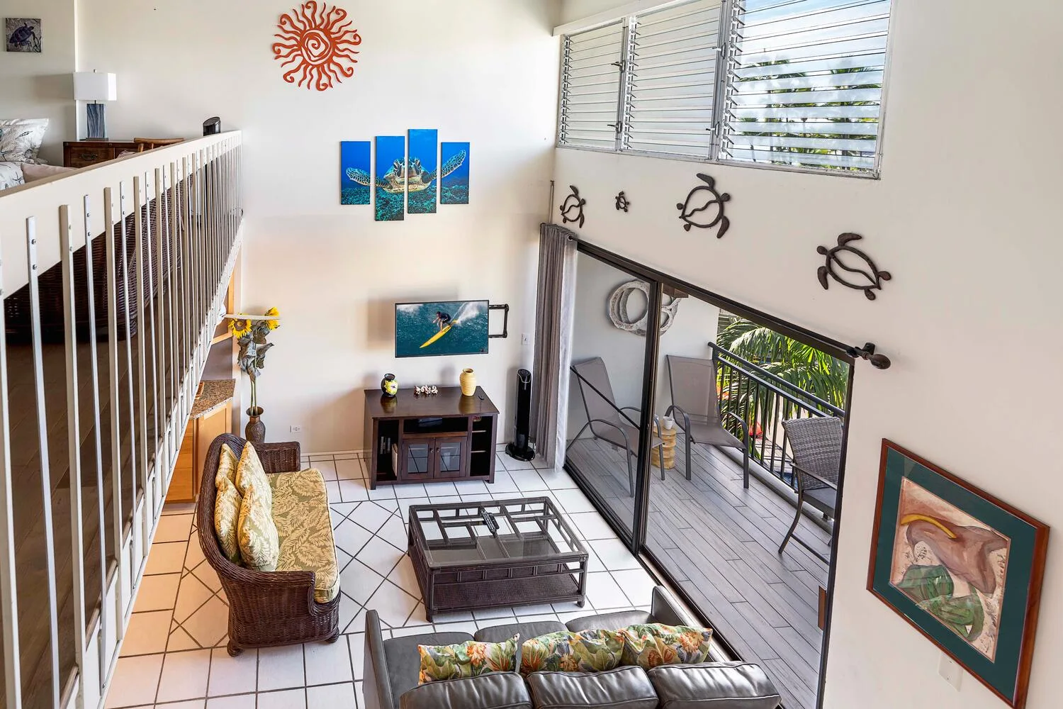 A bright living room opens onto a balcony through large glass doors.