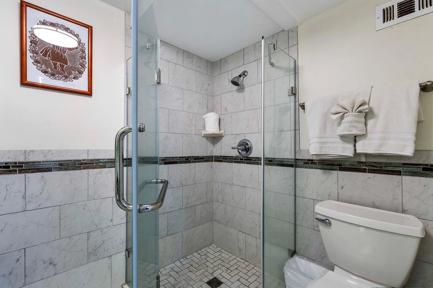 A tiled bathroom with a glass shower and toilet.