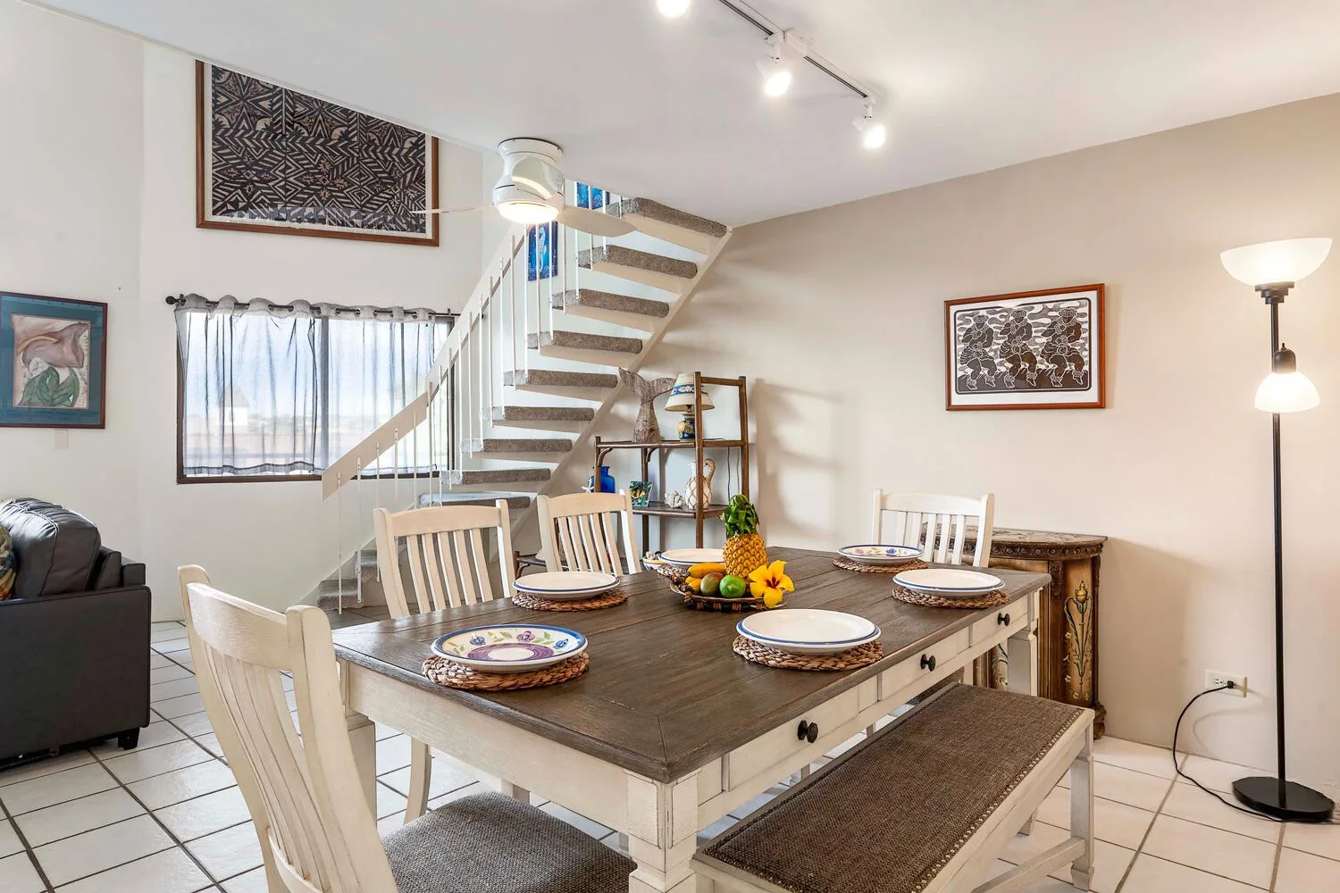 A dining area with a large table set with plates beneath a staircase.